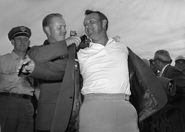 Arnold Palmer, right, slips into his green jacket with help from Jack Nicklaus after winning his fourth Masters golf championship on April 12, 1964. (AP Photo)